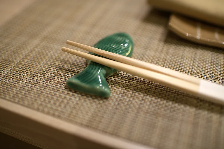 A green ceramic chopstick rest on woven linen