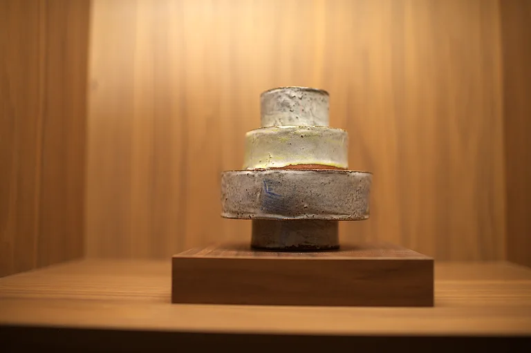 A stacked ceramic sculpture on a walnut plinth