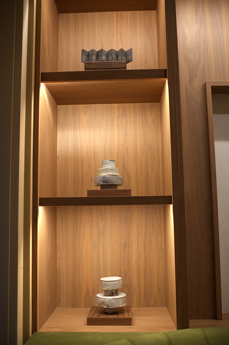 Ceramics on lit oak shelves by the entrance